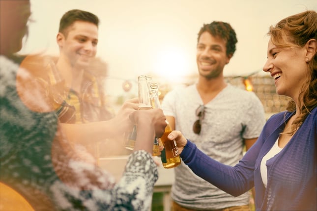 Multi-ethnic millenial group of friends partying and enjoying a beer on rooftop terrasse at sunset.jpeg